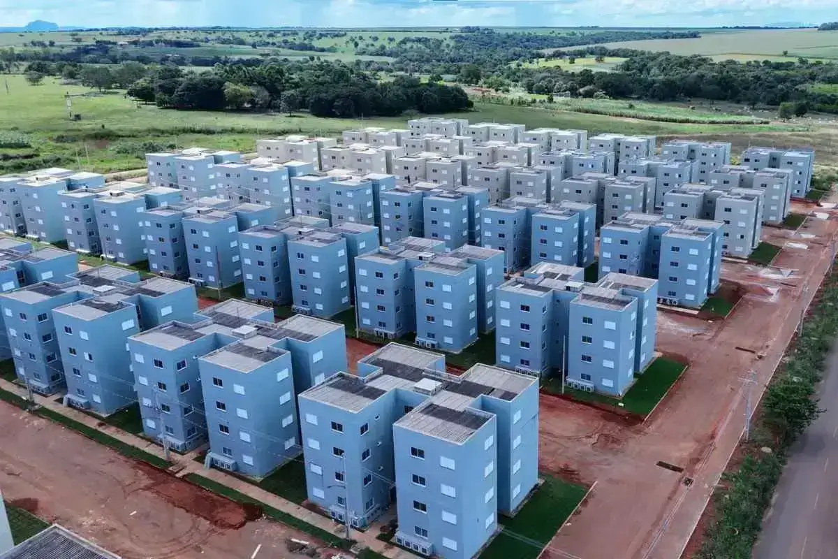 Fachada do Residencial Celina Bezerra em Rondonópolis com famílias felizes, simbolizando habitação social acessível.