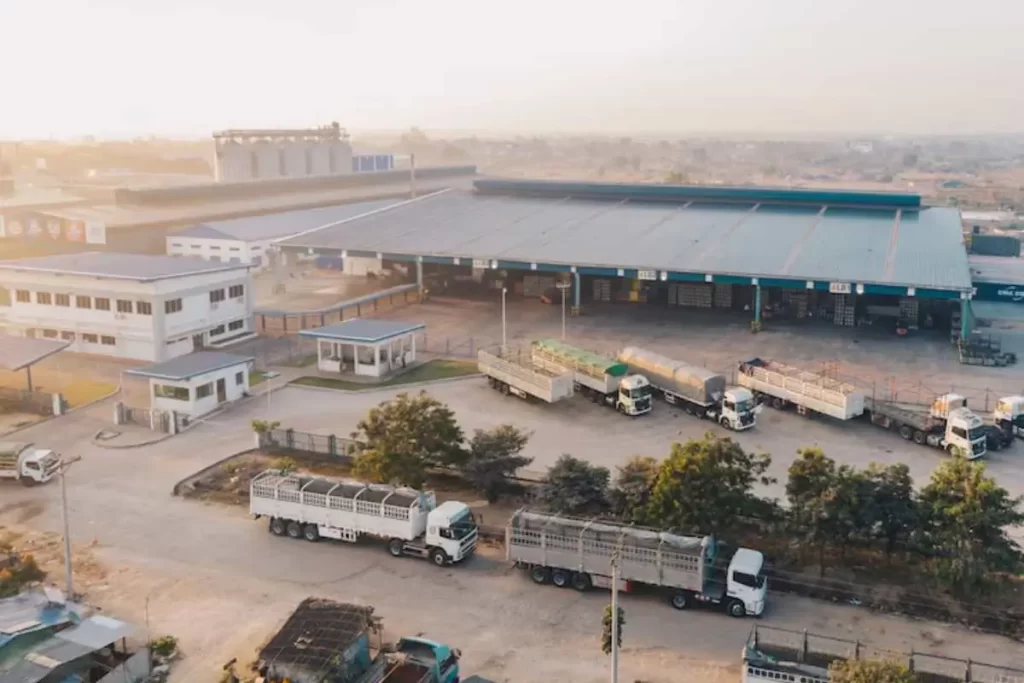 Alta na Importação de Fertilizantes Motor da Safra de Inverno Aquece 2 Caminhões carregados com big bags de fertilizantes em pátio logístico ou deixando terminal portuário, representando a logística de fertilizantes importados no Brasil.
