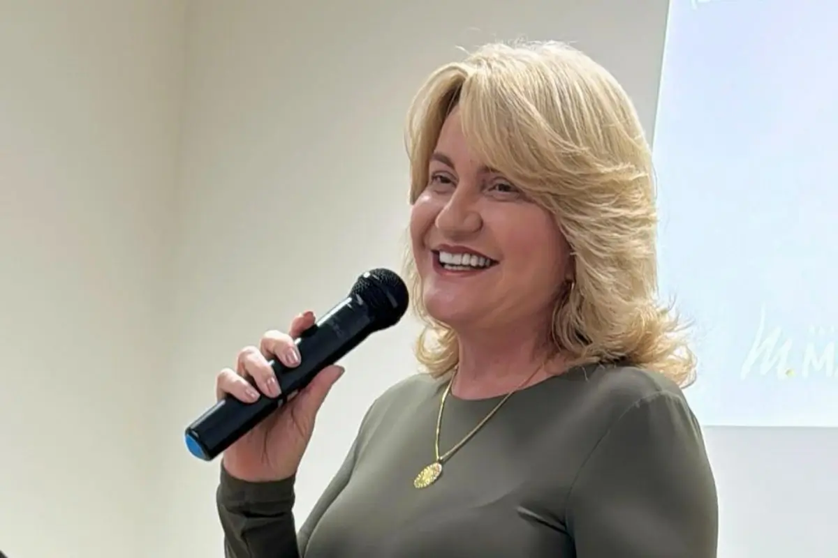 Equipe diversa e sorridente colaborando em um ambiente de trabalho moderno com luz natural, plantas e mesas organizadas, representando qualidade de vida no trabalho.