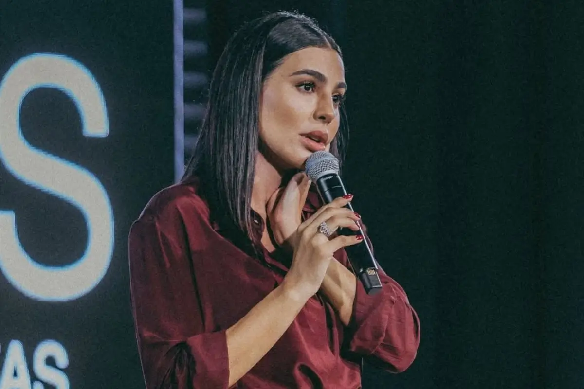 Cintia Chagas segurando microfone no palco do Espaço Ideias Buffet em Rondonópolis diante de plateia atenta