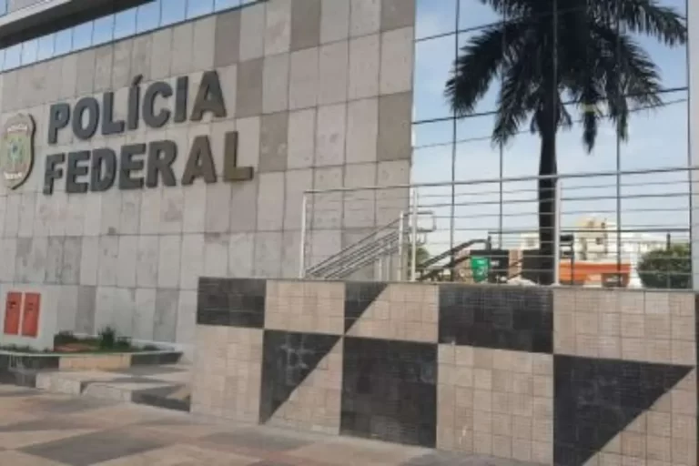 Fachada da Polícia Federal em Cuiabá iluminada à noite durante operação contra fraudes em consignados de servidores de MT