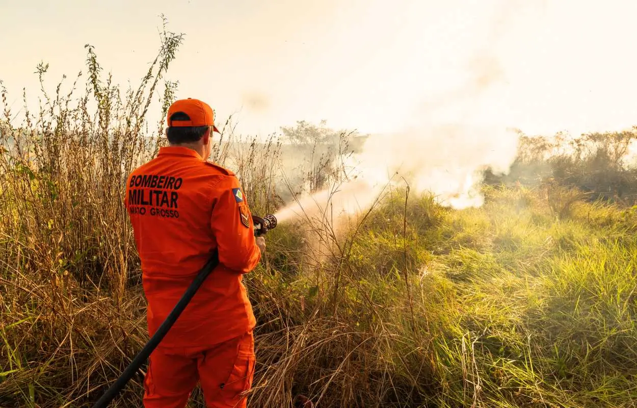 Bombeiro de costas combatendo queimada em área rural durante período seco em Rondonópolis.