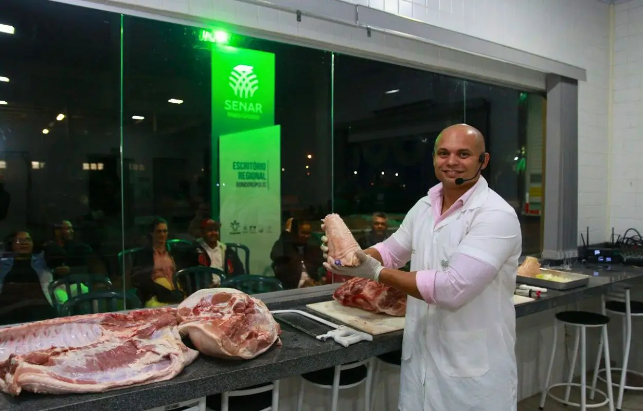 Homem instrutor do Senar MT corta carne bovina em demonstração prática na Vitrine da Carne, durante preparativos para a Exposul 2025 em Rondonópolis.