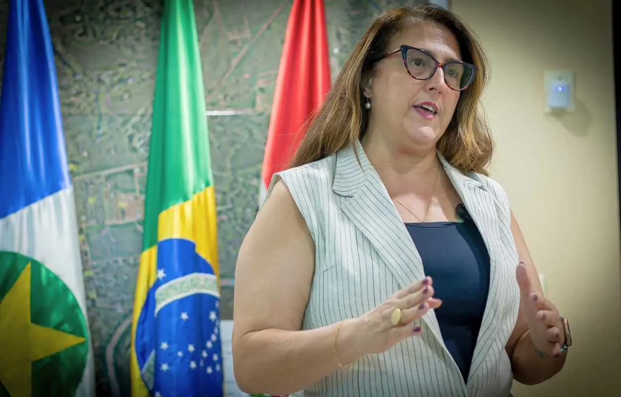 secretária de Fazenda de Rondonópolis Rane Curto sorri em frente a banner da campanha IPTU Premiado