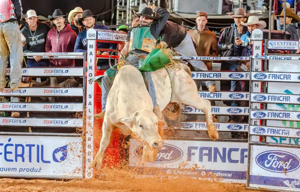 Peão montando touro na Arena João Potero durante a abertura do rodeio da 51ª Exposul em Rondonópolis