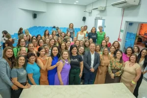 Um grupo de mulheres empreendedoras no auditório da Prefeitura de Rondonópolis. No centro, o prefeito Claudio Ferreira e a secretária Alessandra Ferreira. Todos estão em pé, posicionados de frente para a câmera e sorrindo. A imagem transmite uma postura profissional de união e parceria institucional entre o poder público e o movimento feminino.