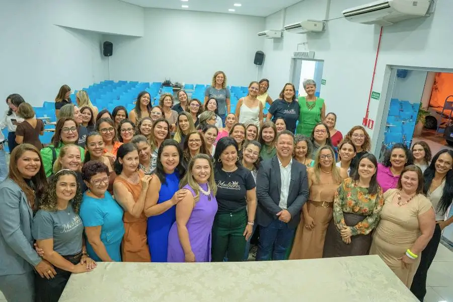 Um grupo de mulheres empreendedoras no auditório da Prefeitura de Rondonópolis. No centro, o prefeito Claudio Ferreira e a secretária Alessandra Ferreira. Todos estão em pé, posicionados de frente para a câmera e sorrindo. A imagem transmite uma postura profissional de união e parceria institucional entre o poder público e o movimento feminino.
