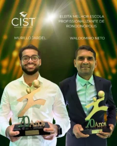 Dois homens sorridentes posicionados lado a lado, segurando troféus dourados com o emblema de 70 anos. O homem à esquerda usa óculos e camisa branca, e o homem à direita veste paletó escuro. A imagem possui um fundo verde com luzes douradas, o logotipo da Cist e o texto informando a eleição de melhor escola profissionalizante de Rondonópolis.